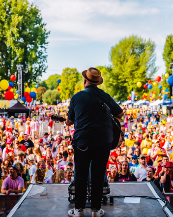 Björn Heuser  mit Hut spielt Gitarre vor großem Open-Air-Publikum