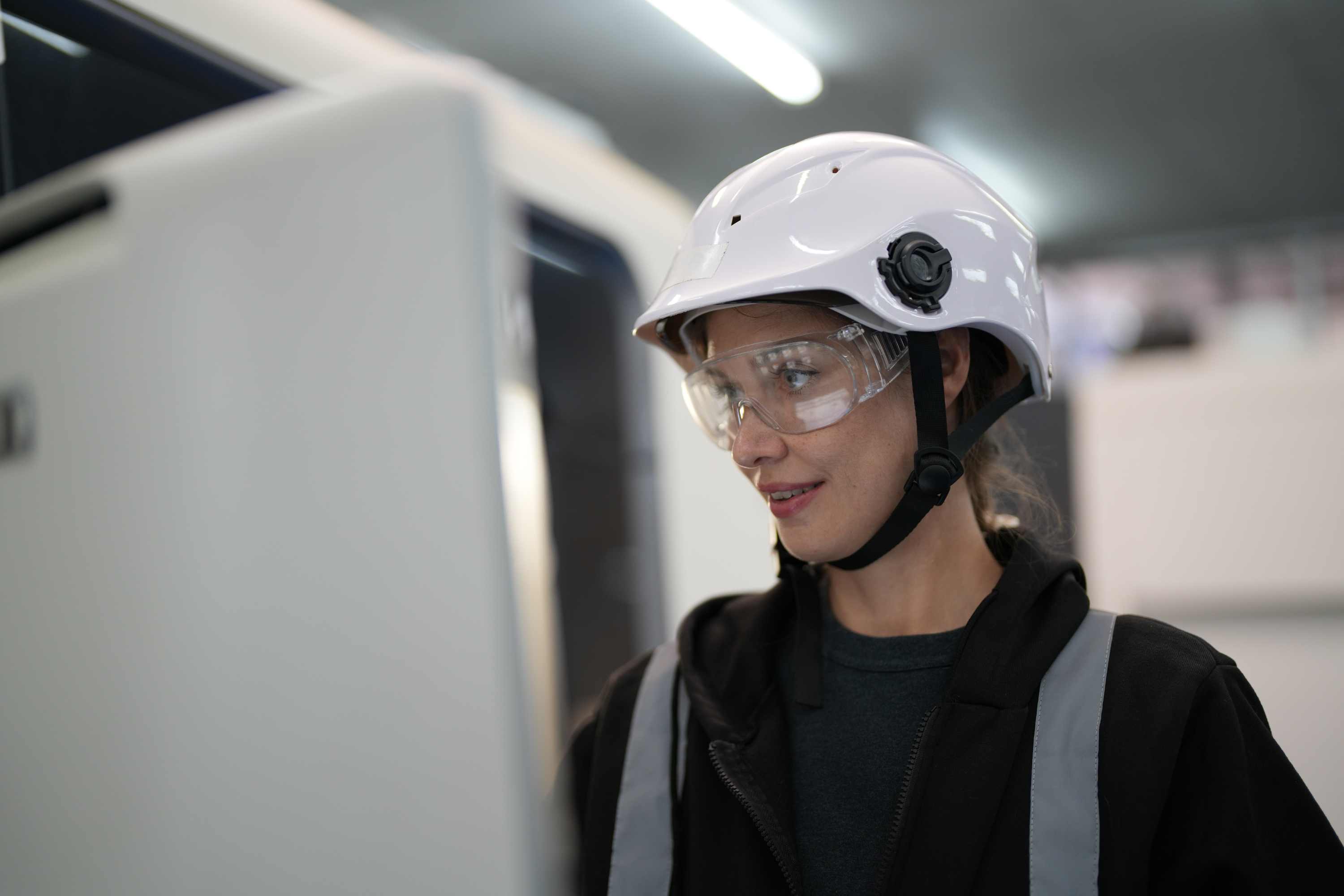Ingenieurin arbeitet am Computer, trägt Helm und Schutzbrille, SL SustainGuard.