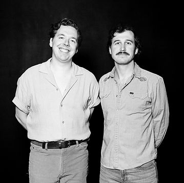 Black and white photo of two men standing side by side, smiling.