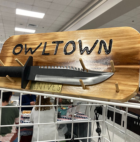 Owltown wooden sign with large knive