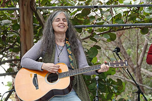 cheryl with guitar at sacred lands 2025.jpg