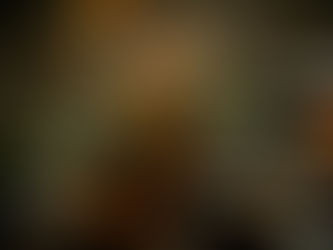 Snow-covered Christmas tree with warm glowing lights in a snowy setting, creating a festive and cozy atmosphere. Blurred lights in background.