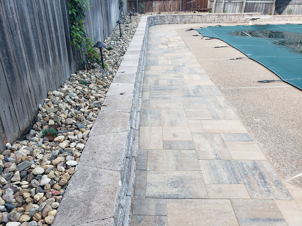 Planted retaining wall with flagstone border around backyard swimming pool by Marshall Grain Company