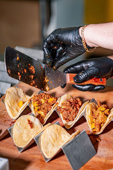 Tacos servidos en mesa con otros tacos vacíos