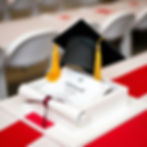gorro de graduación puesto en una mesa blanca de mármol con un diploma enrollado