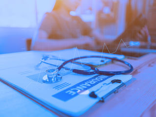 Stethoscope with insurance clipboard and Laptop on desk,Doctor working in hospital writing a prescription, Healthcare and medical concept,test results in background,health care business graph