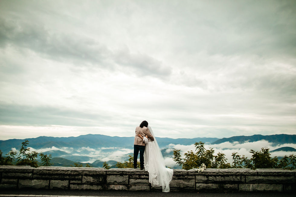 groom holding his brides hand and guiding her through a field as she looking back over her shoulder and smiles