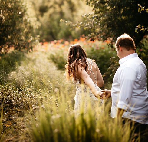 Smoky Mountain elopement with man and woman holding hands as the woman leads the man through a wildflower field as they elope to gatlinburg