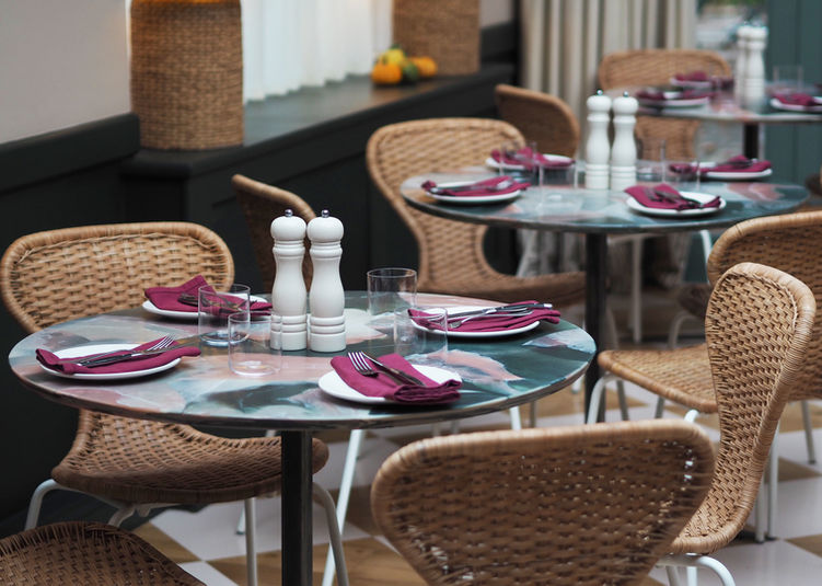 Round recycled plastic restaurant table with marble-effect surface set with plates, napkins and glassware