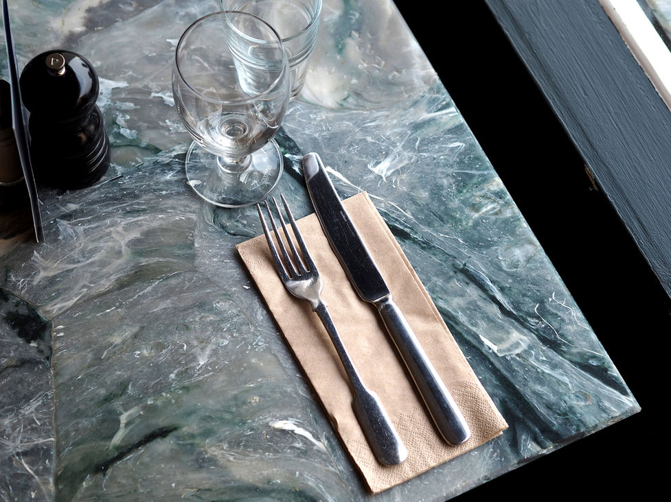 Close-up of recycled plastic tabletop with marble-effect veining in white, grey and deep green tones