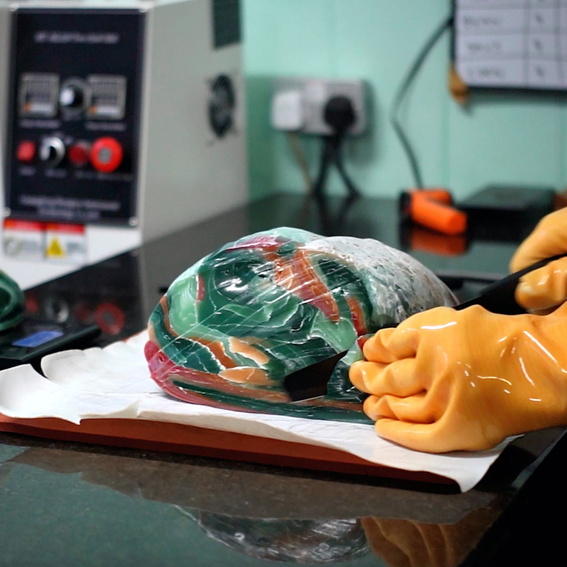 Cutting layered recycled plastic block to reveal marble-effect pattern inside material