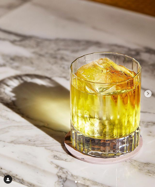 Whisky glass on recycled plastic coaster with marble-effect surface and warm lighting