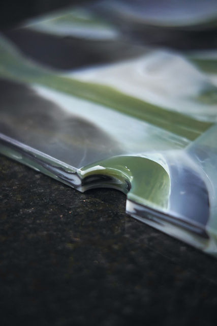 Close-up of recycled plastic surface with green and white marble-effect pattern and CNC cut edge detail