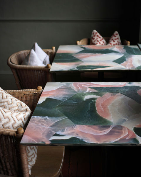 Recycled plastic restaurant tables with marble-effect surfaces in green, pink and white tones in interior setting