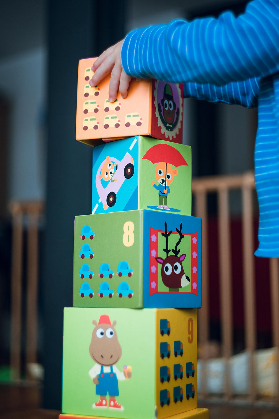 An infant piling up toys at one of the infants room during indoor playtime.