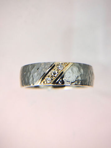 Men's two toned wedding band with three diamonds set on a diagonal in yellow gold with a 14k white gold hammered finished band