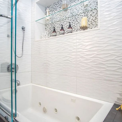 Luxurious Marathon, FL main suite bath with spa-style jetted tub, elegant glass enclosure, and coastal-inspired tile accents