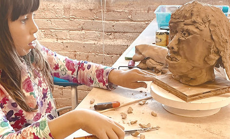 Child working on a ceramic sculpture of a head
