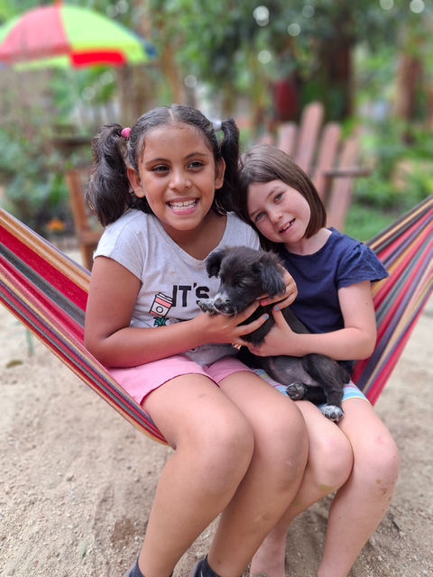 Two girls in hammock holding a puppy at the worlds school in antigua guatemala