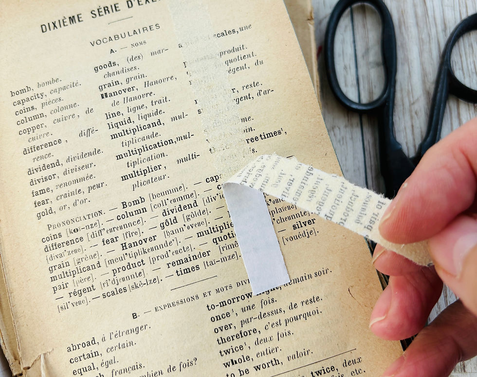 An artist using double sided tape to remove text from an old page to create washi tape.
