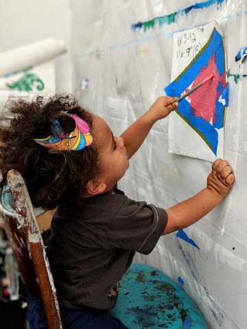 young child assisting with mural in studio