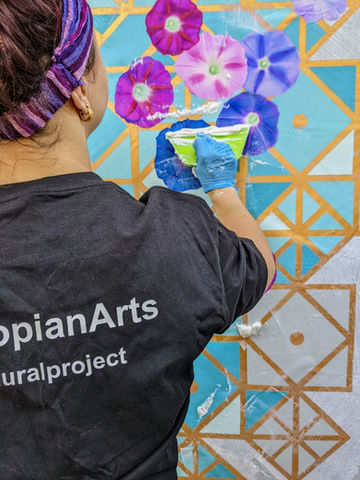 kala installing mural with geometric patterns