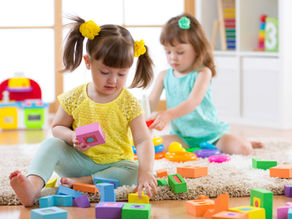 Two young children playing separately with blocks