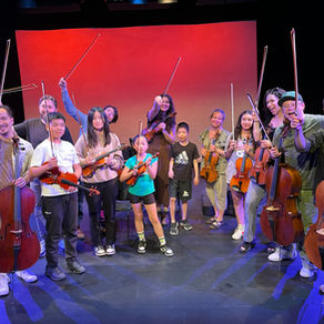 Kids and adult teachers holding cellos and violin bows while smiling