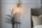 Our cozy primary bedroom corner with a softly glowing wall sconce, a textured decorative pillow, and a vase of dried eucalyptus, creating a warm and inviting ambiance.