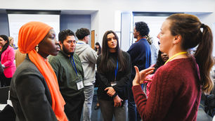 A group of young professionals speaking at a networking event in Washington, DC, three people are looking at one speaker