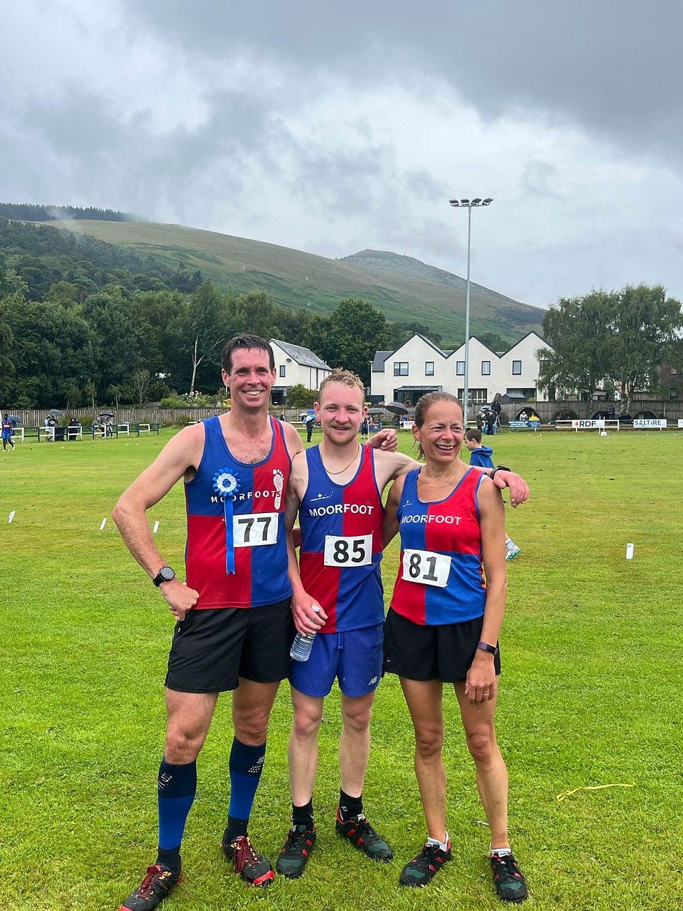 Three runners in team kit in a grassy field