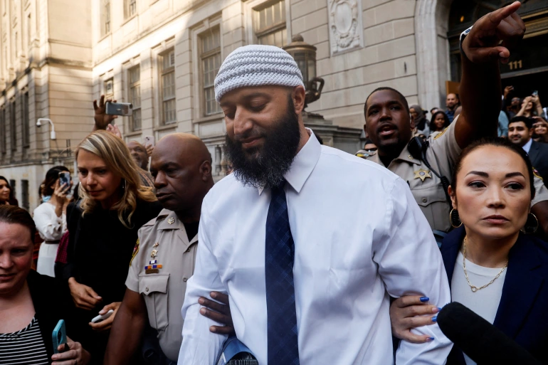 A picture of Adnan Syed leaving prison, with his lawyer holding his arm.