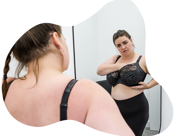 Model is reaching into the cup of a black bra to scoop her breast tissue into the centre.