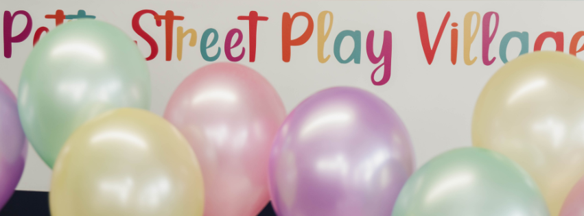 pastel coloured birthday party balloons arranged infront of the petite street play village wall decal