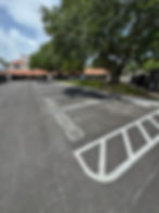 White RESERVED pavement stencils and a striped no parking zone painted in an office complex parking lot in Pensacola, FL