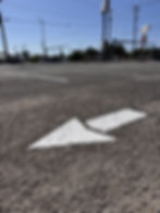 Newly painted white directional traffic arrow on an asphalt parking lot in Pensacola, FL