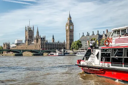 Imagen de un barco navegando en el río Támesis con el Big Ben de fondo, lugar al que puedes acudir con los mejores viajes a Londres.