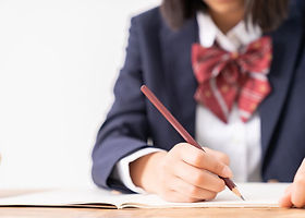 ノートに文字を書く制服の学生