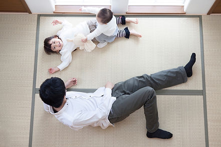畳に寝転ぶ父親と子ども
