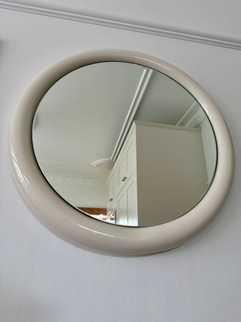 A cream coloured round metal framed wall mirror for use in bathrooms, bedrooms, dressing rooms etc.