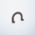 A bronze arc shaped wall hook is seen mounted on a white wall