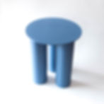 A blue aluminium stool / side table is seen in front of a white background