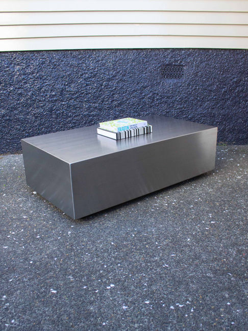 A rectangle shaped solid stainless steel coffee table styled with coffee table books