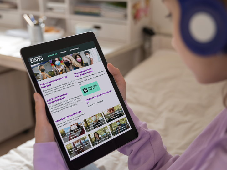 Tablet in young person's hands displaying the home page of a website