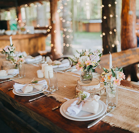 Rustic wedding reception table decorated with fresh flowers in mason jars, candles, and wood accents at S&S Ranch barn venue
