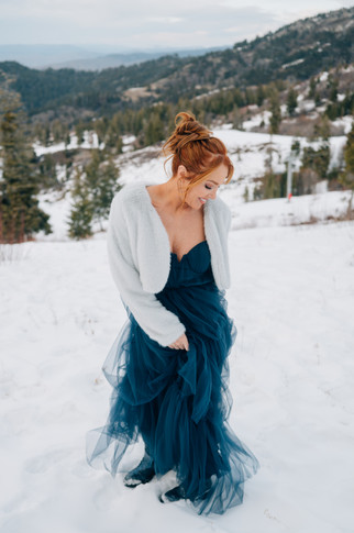 Two women in blue and purple gowns standing in snow at Bogus Basin, Idaho.sin winter portraits near Boise