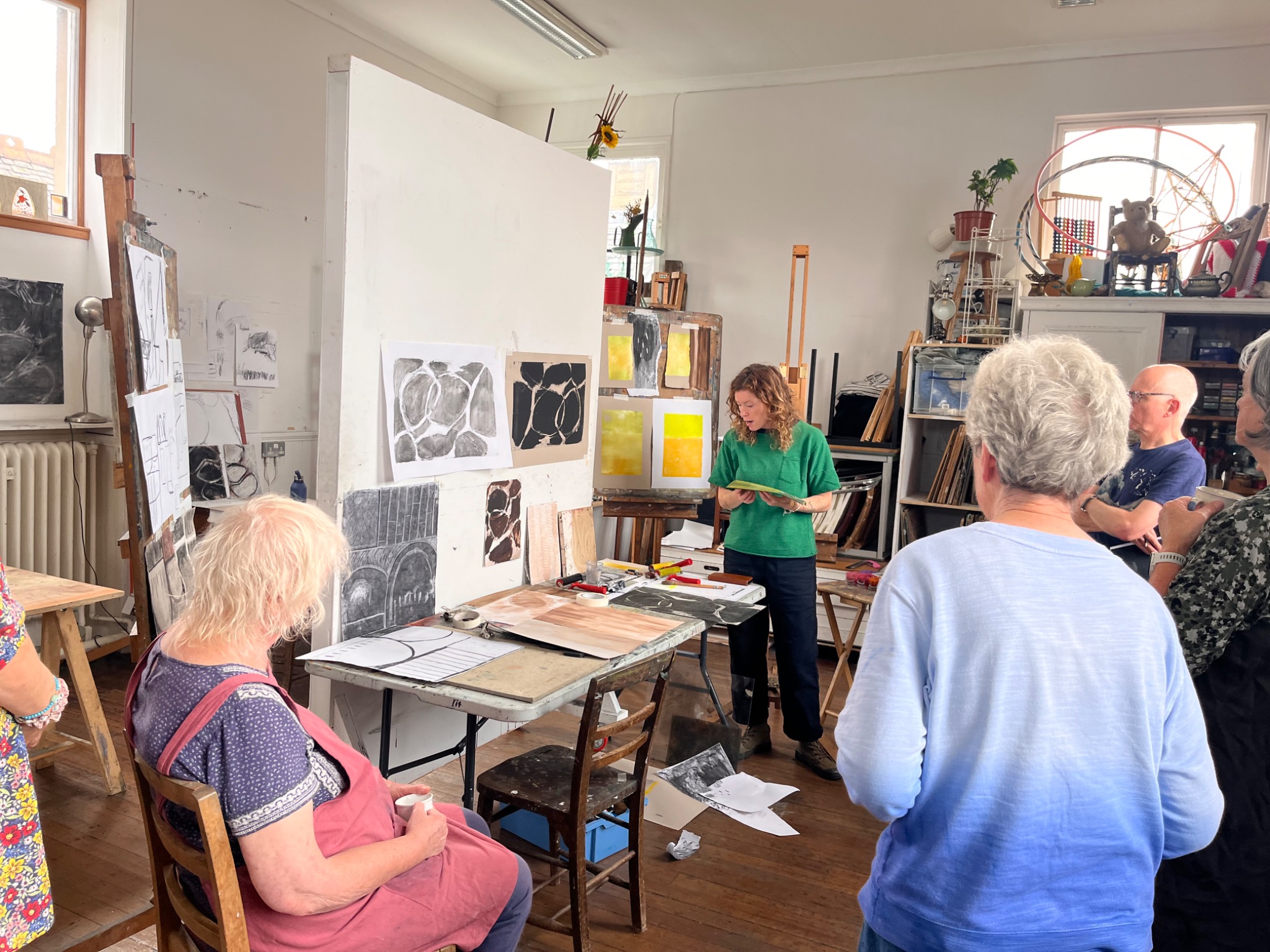 Ginny Elston leading a group discussion surrounded by workshop drawings and prints