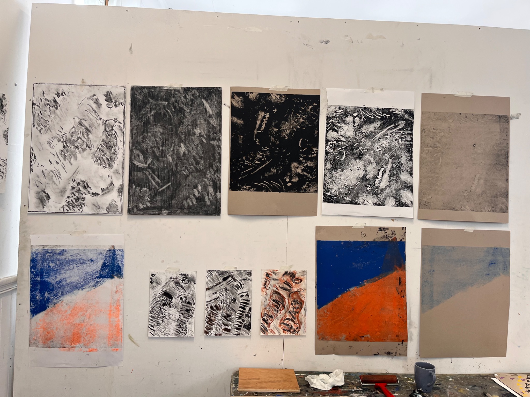 Wall display of monochrome experimental drawings and blue-and-orange abstract studies
