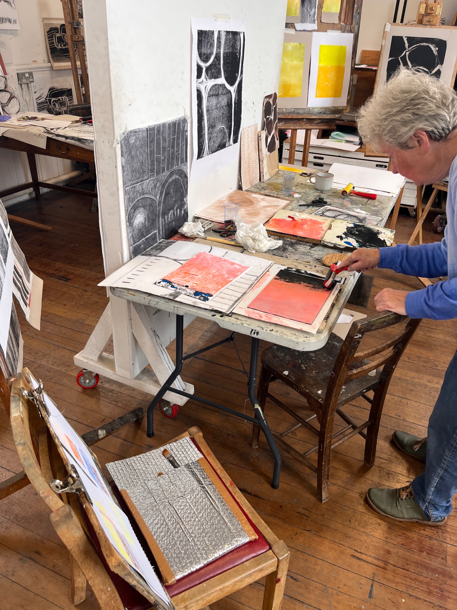 Participant rolling ink onto a plate during the monotype printmaking session