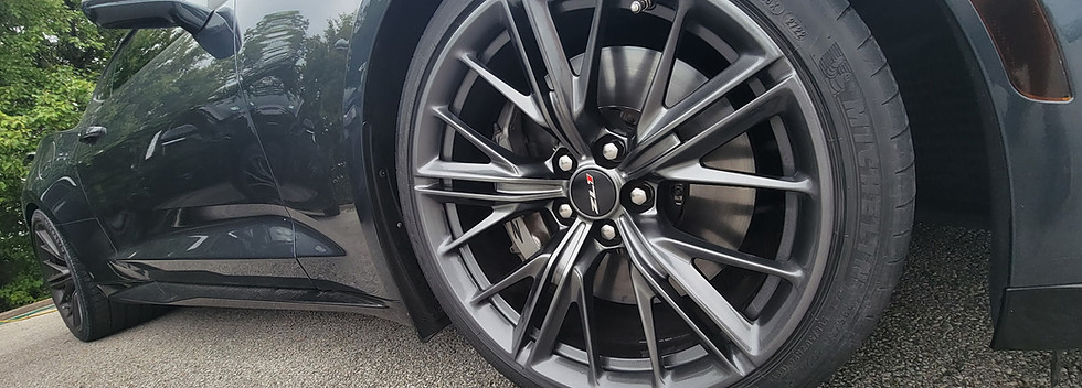 Close-up of a black sports car's multi-spoke wheel rim.